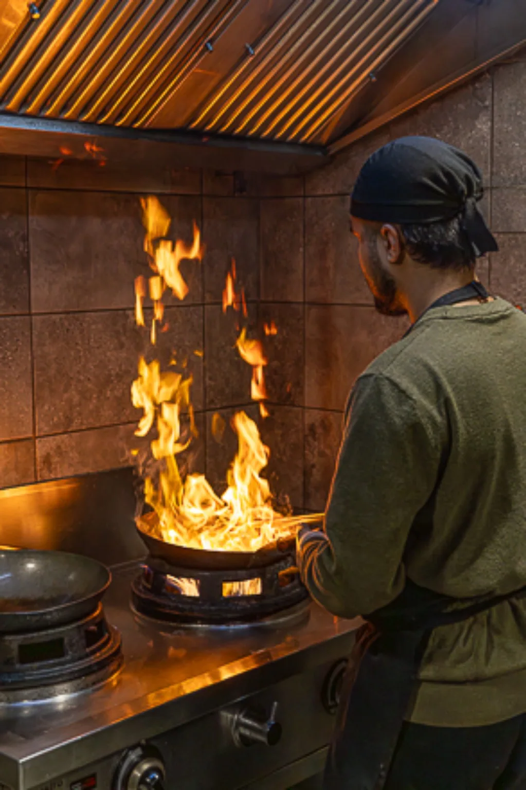 Chef Kin Khao travaillant un wok en flammes