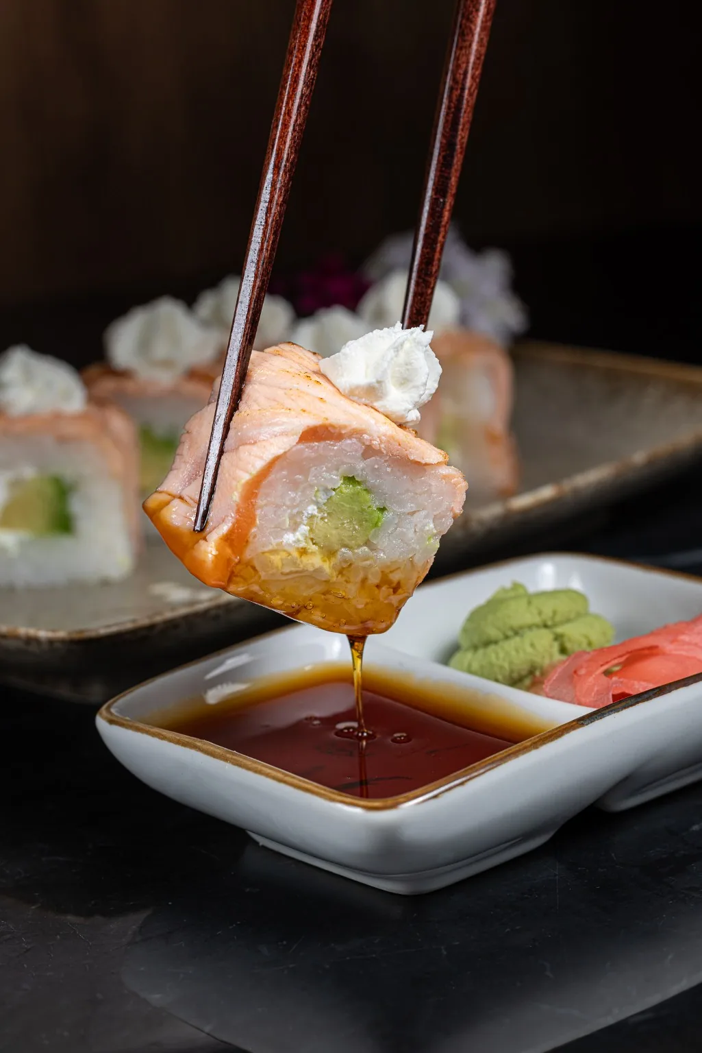 Gros plan sur un sushi Kin Khao trempé dans la sauce